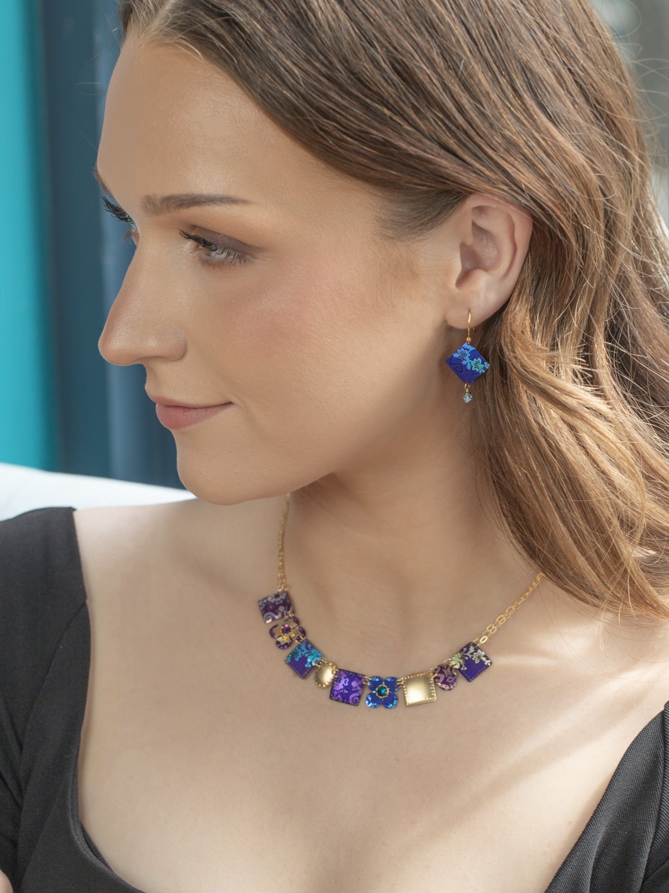 Woman wearing a colorful necklace and earrings against a blue background