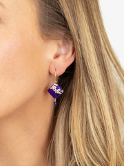 Close-up of a woman wearing a purple beaded earring with gold accents.