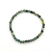Round beaded bracelet with green and black stones on a white background