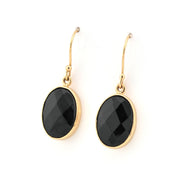 Gold earrings with black oval stones on a white background