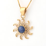 Gold sun-shaped pendant with a blue stone on a white background