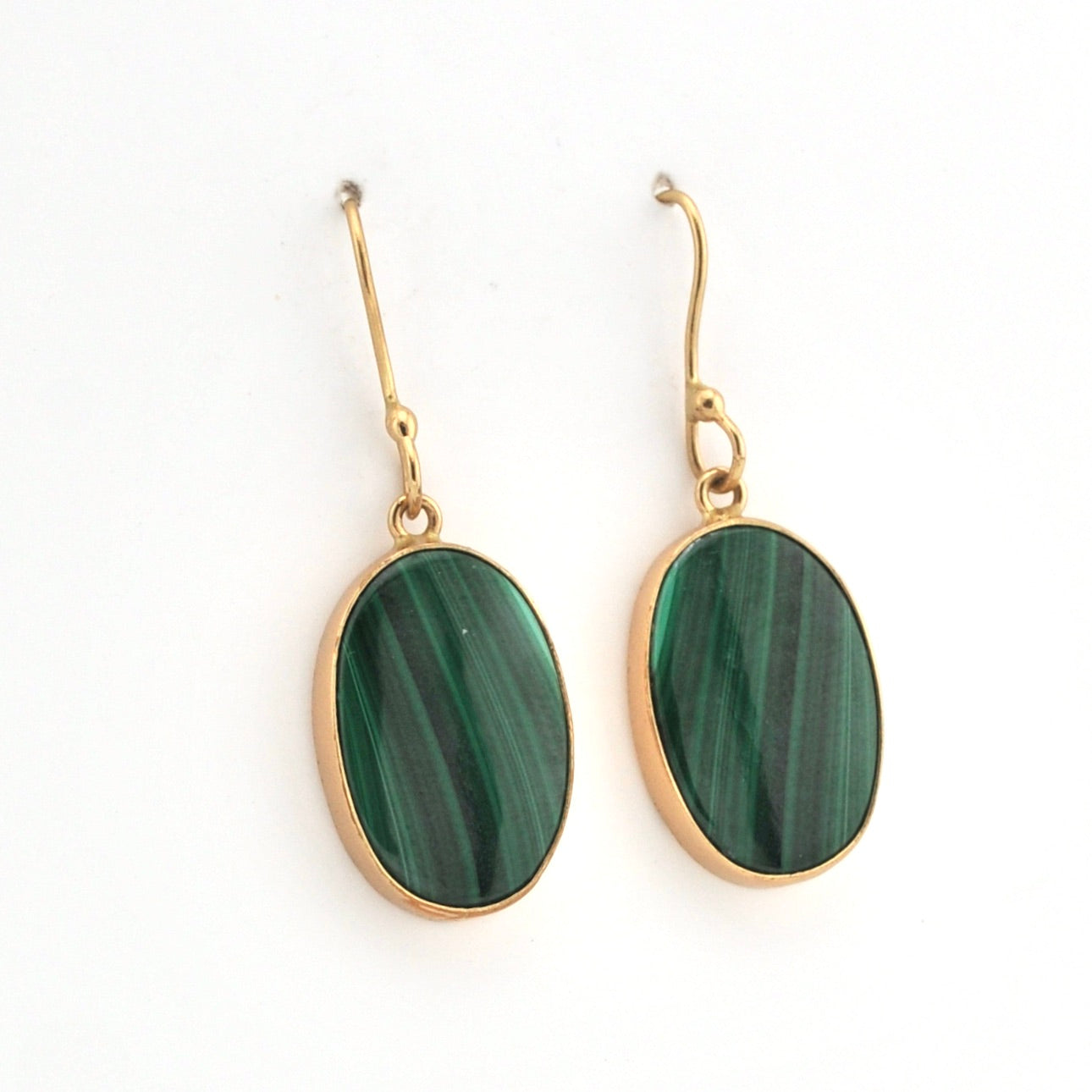 Gold-framed green stone earrings on a white background
