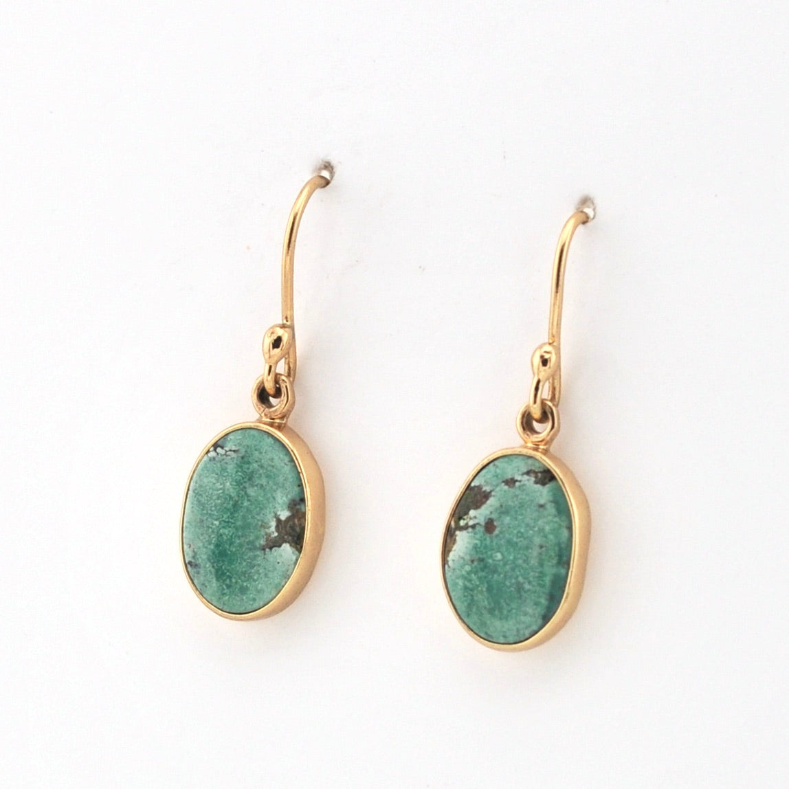Gold earrings with greenstone drops on a white background