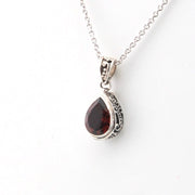Silver pendant with a red gemstone on a white background