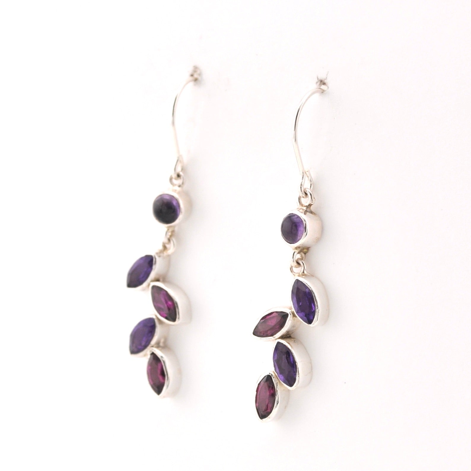Silver earrings with purple gemstones on a white background