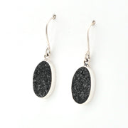 Black oval earrings with silver hooks on a white background