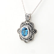 Silver pendant with blue gemstone on a white background