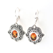 Pair of silver earrings with amber-colored stones on a white background