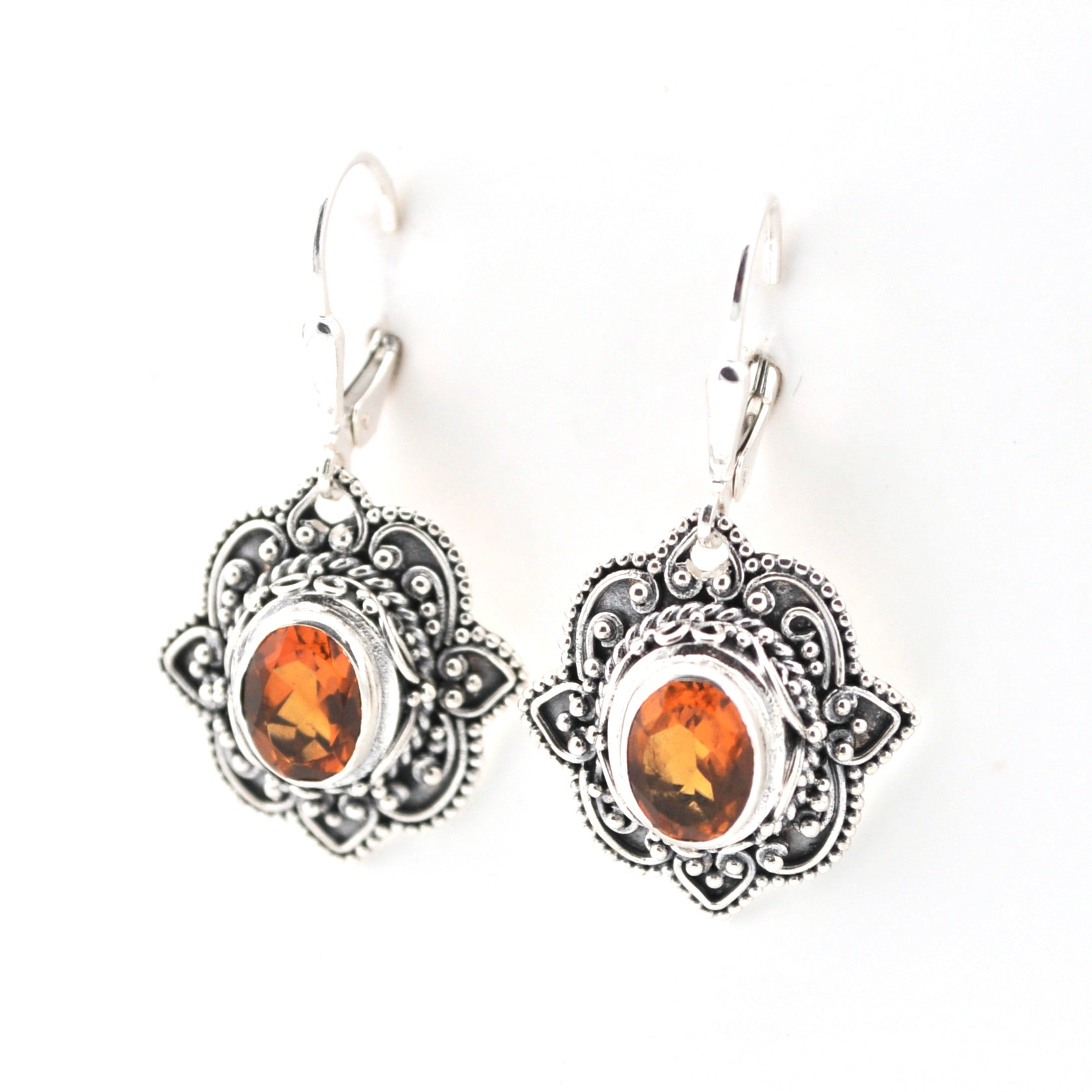 Pair of silver earrings with amber-colored stones on a white background