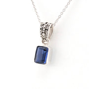 Silver pendant with a blue gemstone on a white background