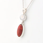 Necklace with a pendant featuring a red stone and white shell on a white background
