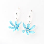 Pair of light blue flower-shaped earrings on a white background