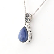 Silver pendant with a blue teardrop-shaped gemstone on a white background