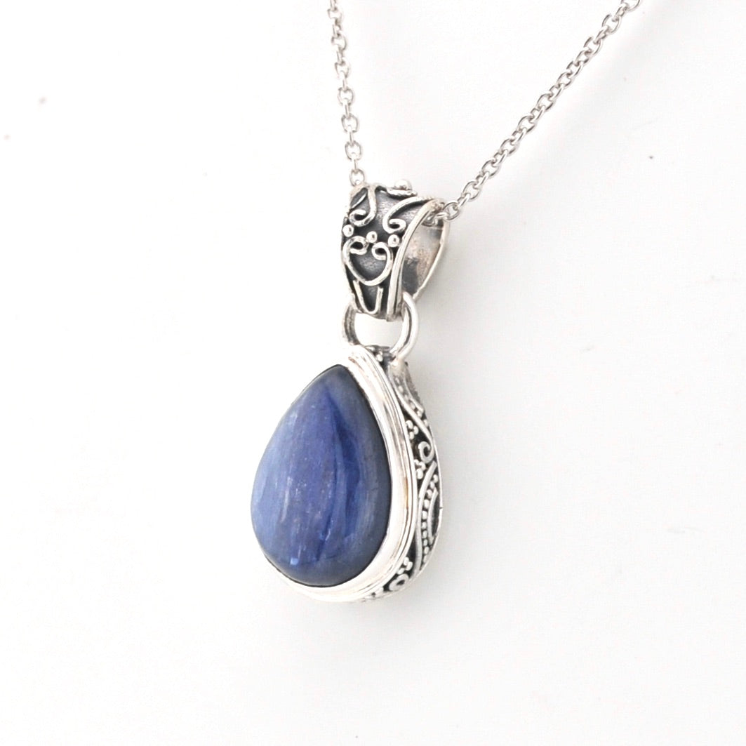 Silver pendant with a blue teardrop-shaped gemstone on a white background