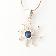 Silver sun-shaped pendant with a blue gemstone on a white background