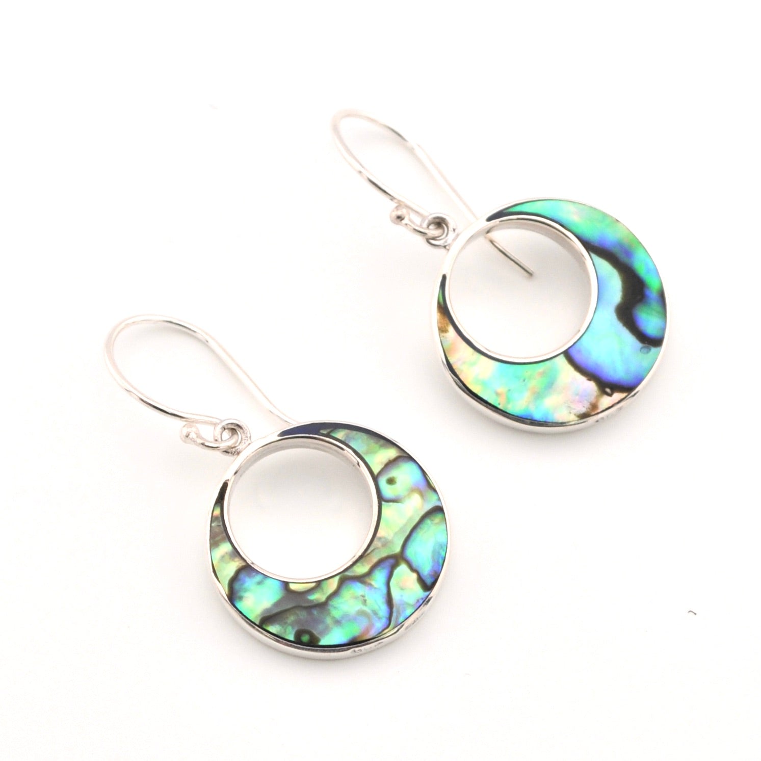 Pair of earrings with circular design with abalone shell on a white background