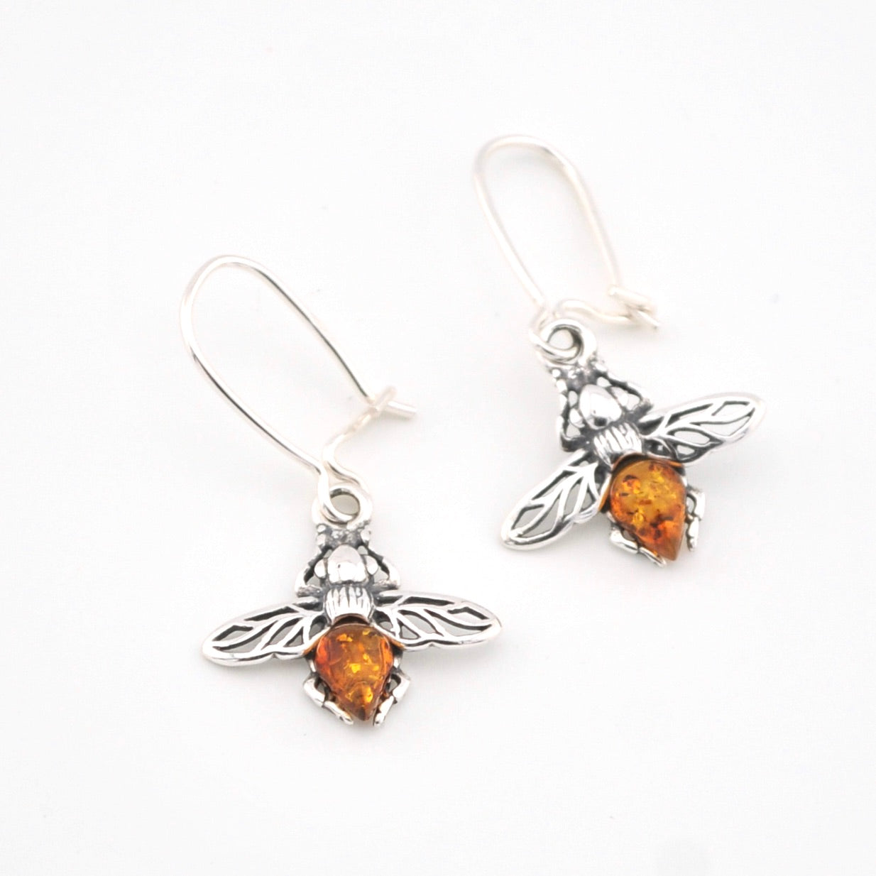 Silver bee earrings with amber stones on a white background