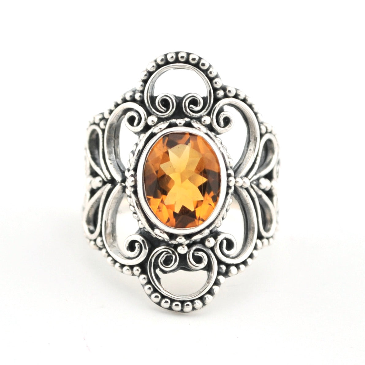 Silver ring with an orange gemstone on a white background