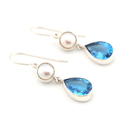 Pair of earrings with pearls and blue teardrop-shaped gemstones on a white background