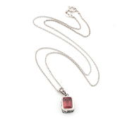 Silver necklace with a red pendant on a white background