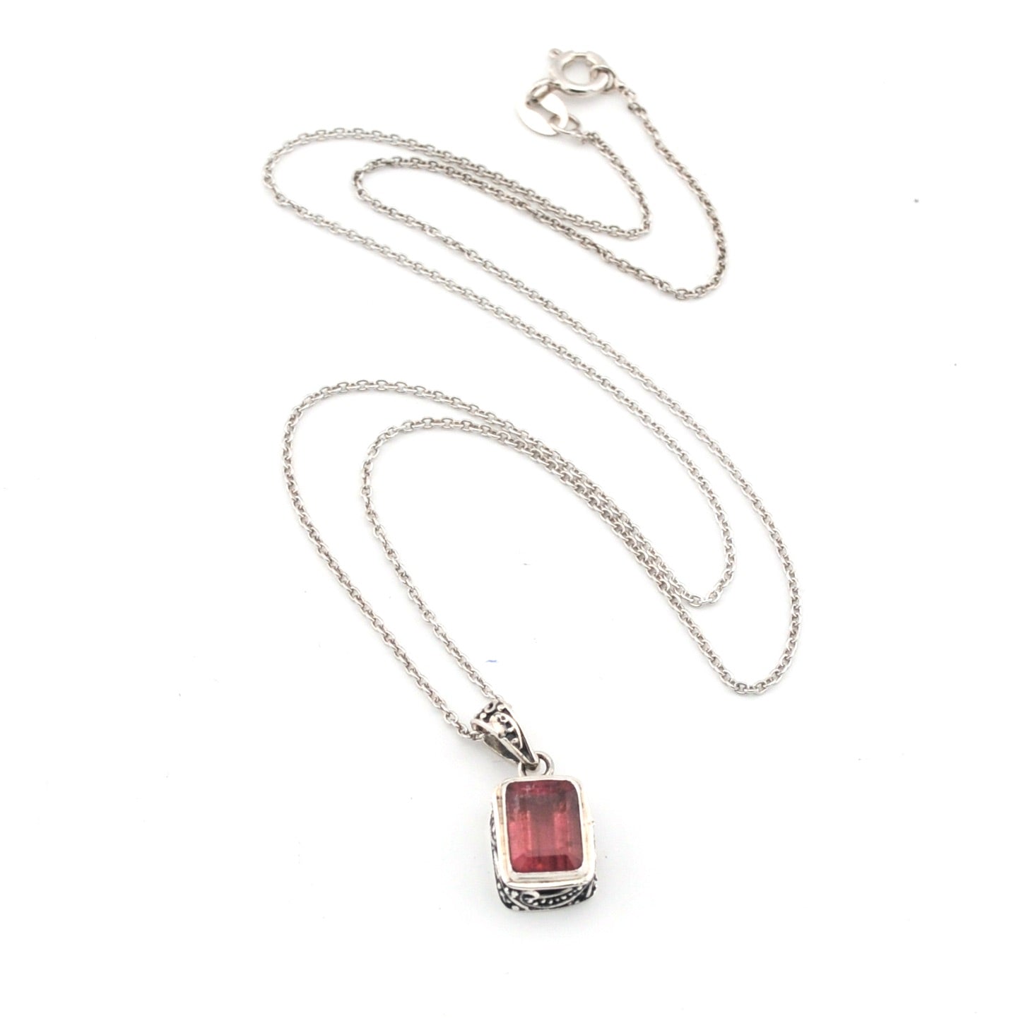 Silver necklace with a red pendant on a white background