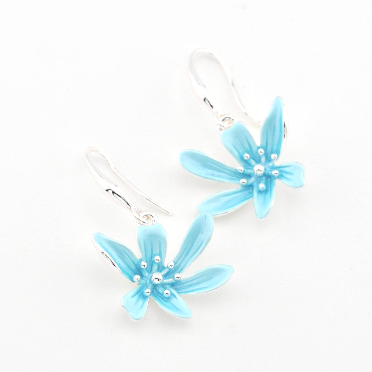 Pair of light blue flower-shaped earrings on a white background