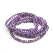Stack of purple beaded bracelets on a white background