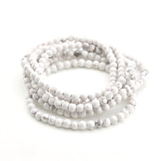 Stack of white beaded bracelets on a white background