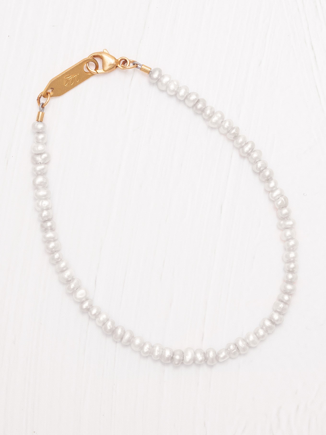 Pearl bracelet with a gold clasp on a white background