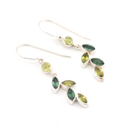Pair of silver earrings with green gemstones on a white background
