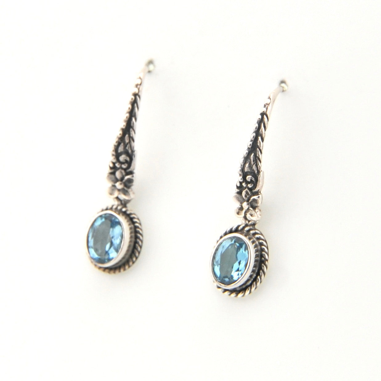 Pair of silver earrings with blue gemstones on a white background