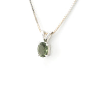 An oval-cut green gemstone pendant in a silver-toned setting, suspended from a delicate silver chain against a plain white background.