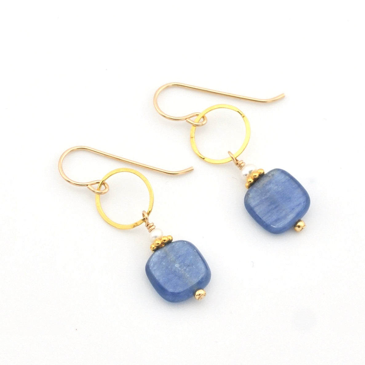 Gold earrings with blue stone drops on a white background