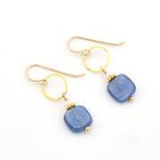 Gold earrings with blue stone drops on a white background