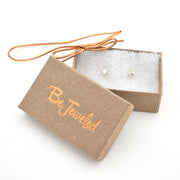 Jewelry box with 'Be Jeweled' branding and a pair of earrings inside on a white background