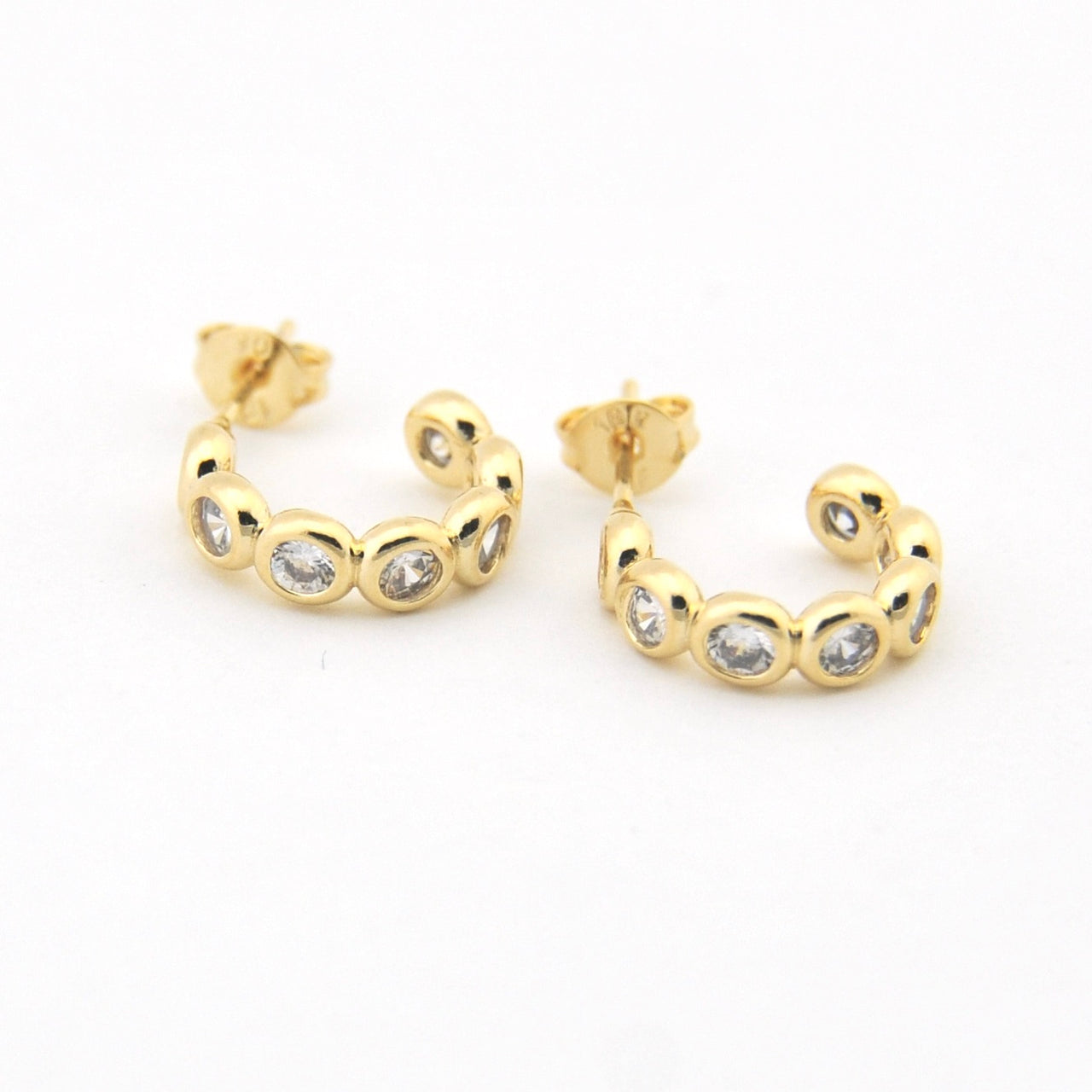 Gold hoop earrings with embedded stones on a white background