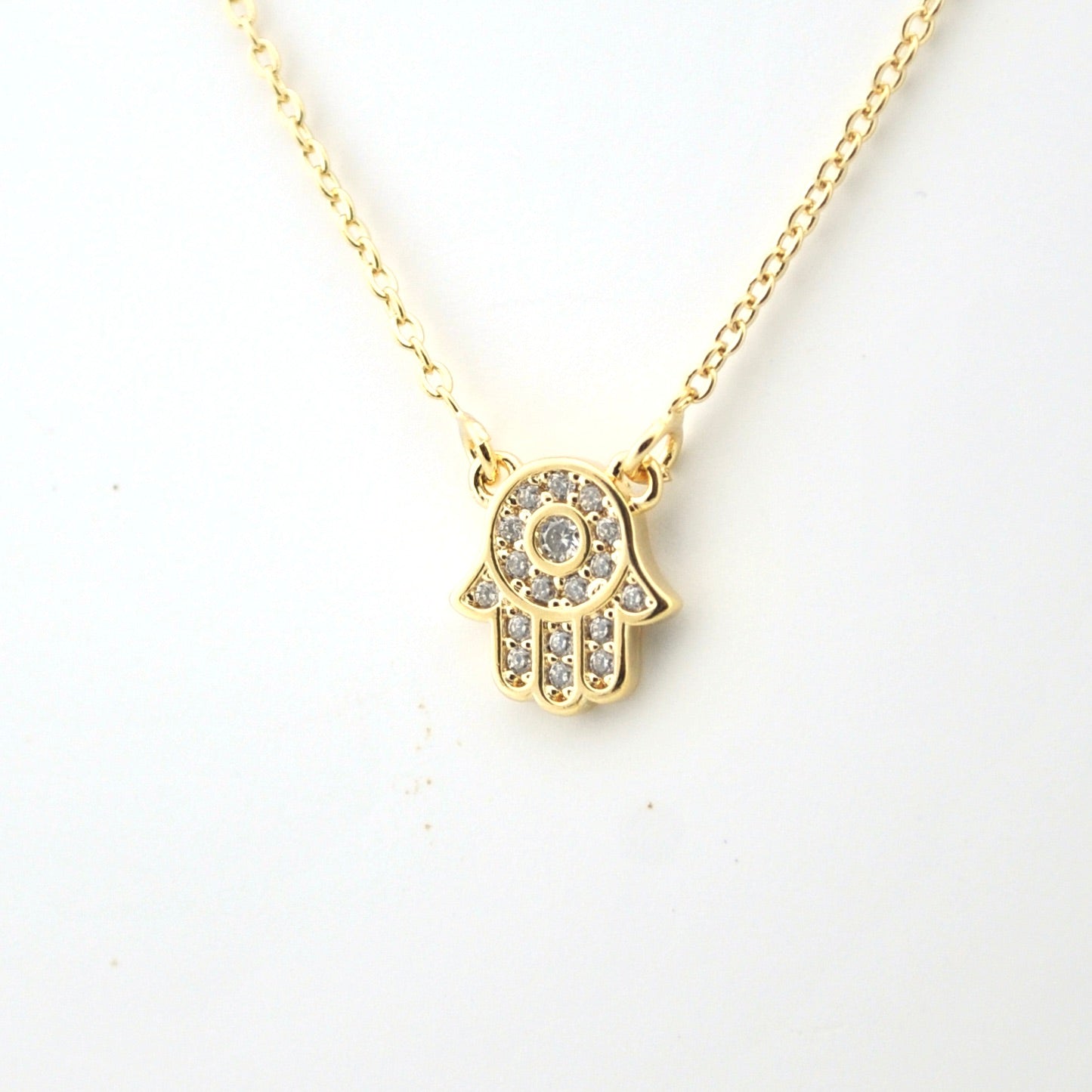 Gold necklace with a Hamsa hand pendant on a white background