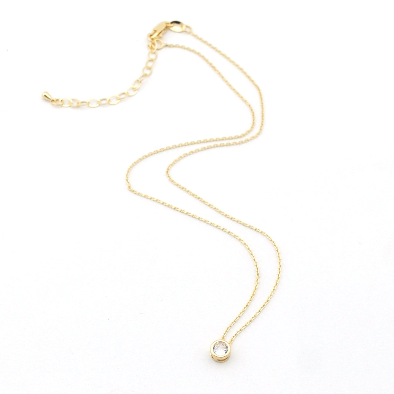 Gold necklace with a small pendant on a white background