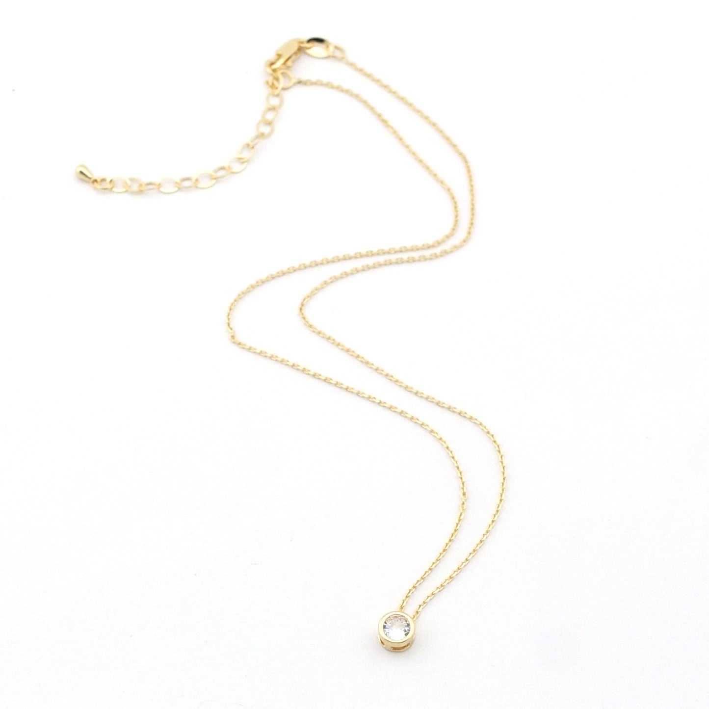 Gold necklace with a small pendant on a white background