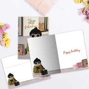 Greeting card with a dog illustration and 'Happy Birthday' text on a white surface with flowers.