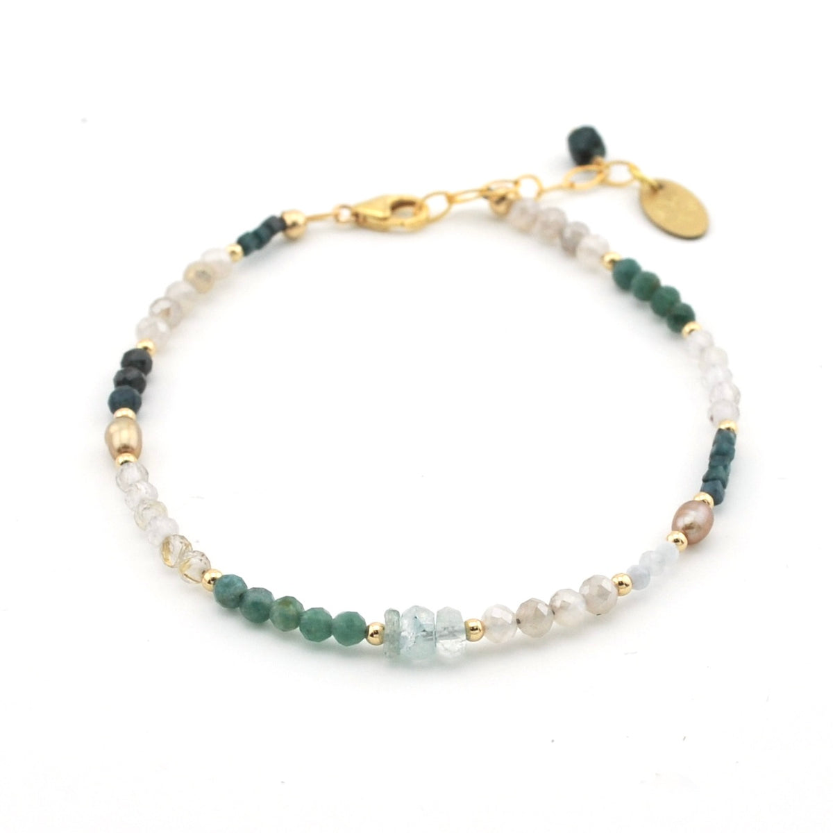 A delicate beaded bracelet featuring green, white, and light blue beads separated by small gold spacer beads, with a gold clasp and a small oval tag, shown on a plain white background.