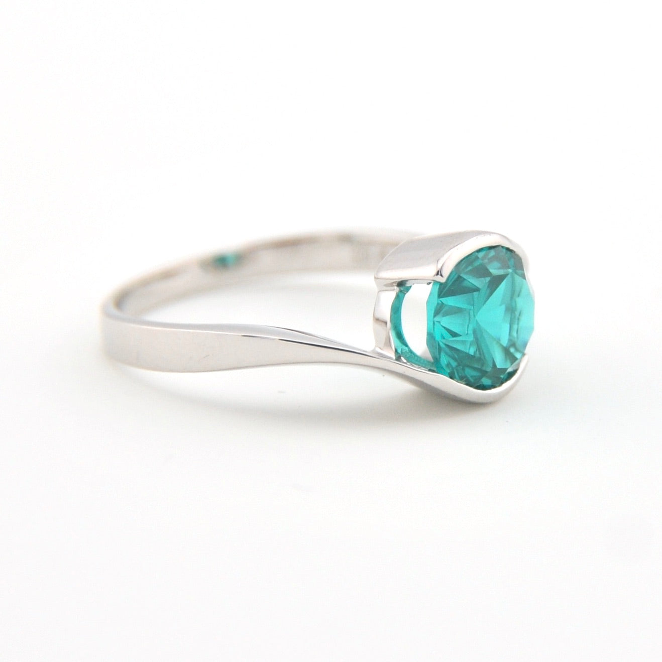 Silver ring with a teal gemstone on a white background