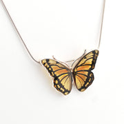 Butterfly-shaped pendant on a chain against a white background