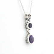 Silver necklace with purple gemstones on a white background