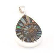 Teardrop-shaped pendant with multicolored stone and silver frame on a white background