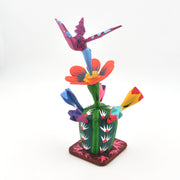 Colorful wood sculpture of a cactus with flowers and birds on a white background