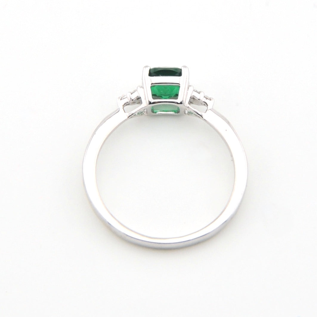 Silver ring with green gemstones on a white background