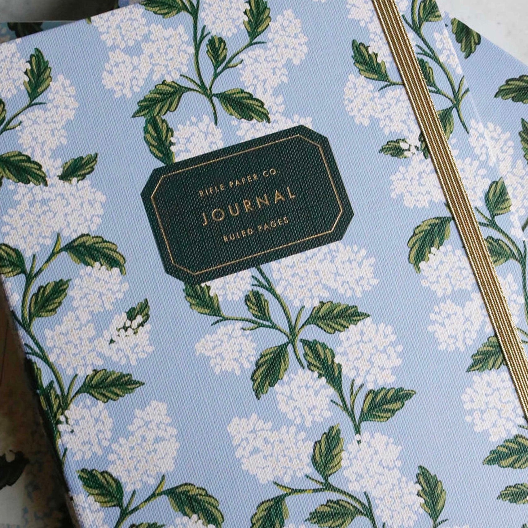 Journal with floral design and visible brand name on a light blue background