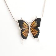 Butterfly-shaped pendant on a chain against a white background