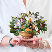 Bouquet of flowers and decorative elements held in hands against a white background